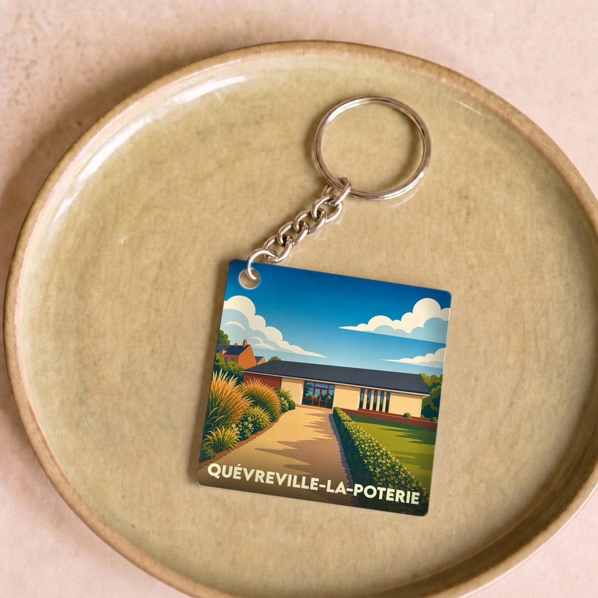 Porte-clés souvenir de Quévreville-la-Poterie avec une illustration stylisée et colorée de la ville.