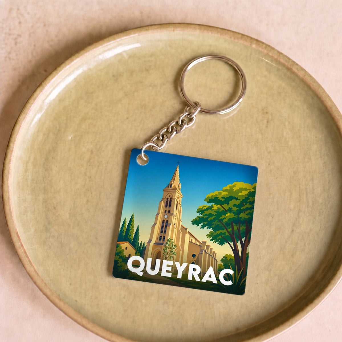 Porte-clés souvenir de la ville de Queyrac avec une illustration stylisée.