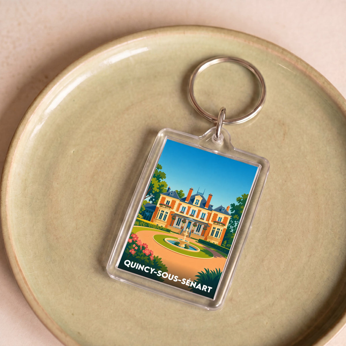 Porte-clés souvenir de la ville de Quincy-sous-Sénart avec une illustration stylisée d'une demeure bourgeoise.