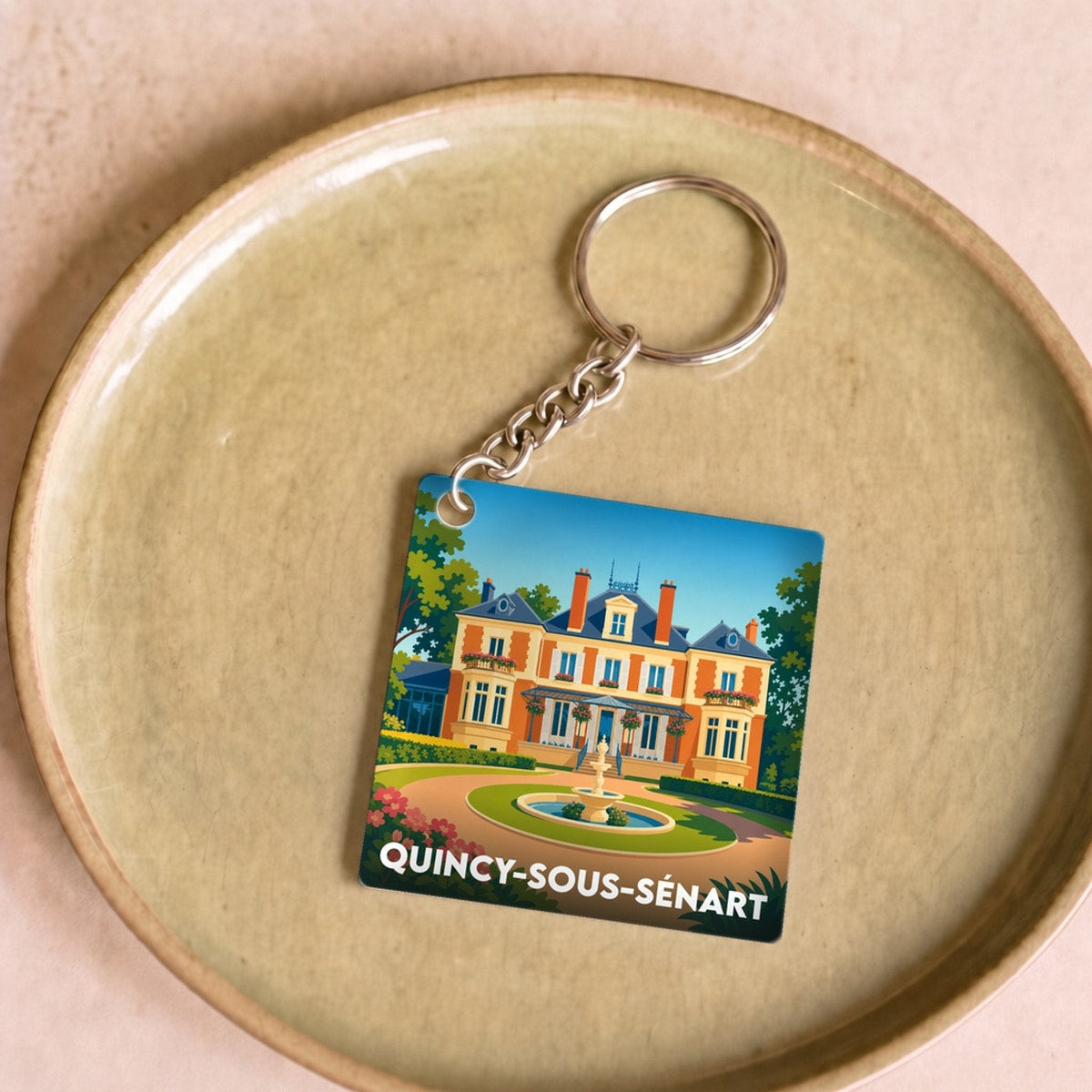 Porte-clés souvenir de la ville de Quincy-sous-Sénart avec une illustration stylisée d'une demeure bourgeoise.