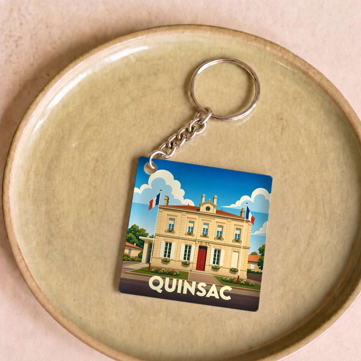 Porte-clés souvenir de la ville de Quinsac avec une illustration stylisée de sa mairie.