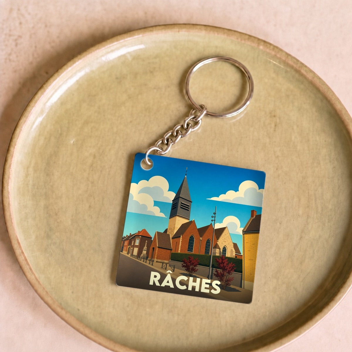 Porte-clés souvenir de la ville de Râches avec une illustration stylisée.