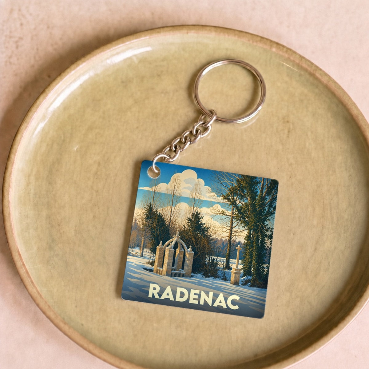 Porte-clés souvenir de la ville de Radenac avec une illustration stylisée d'un monument sous la neige.
