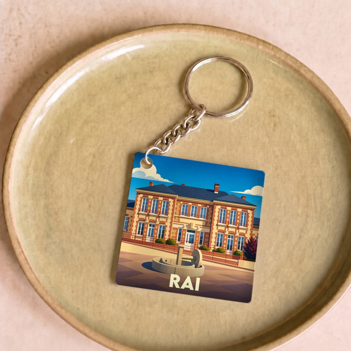 Porte-clés souvenir de la ville de Rai avec une illustration stylisée.