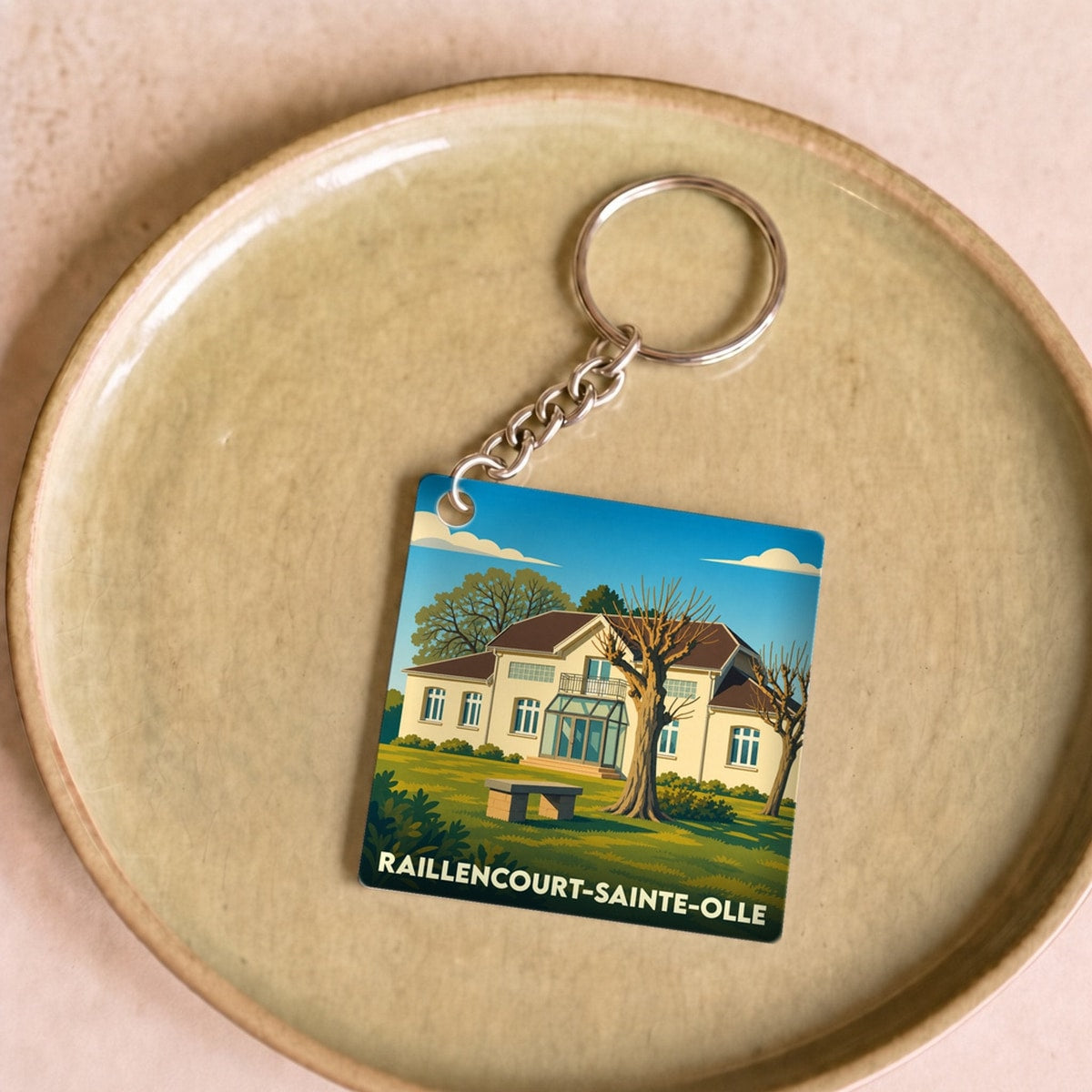 Porte-clés souvenir de la ville de Raillencourt-Sainte-Olle avec une illustration stylisée.