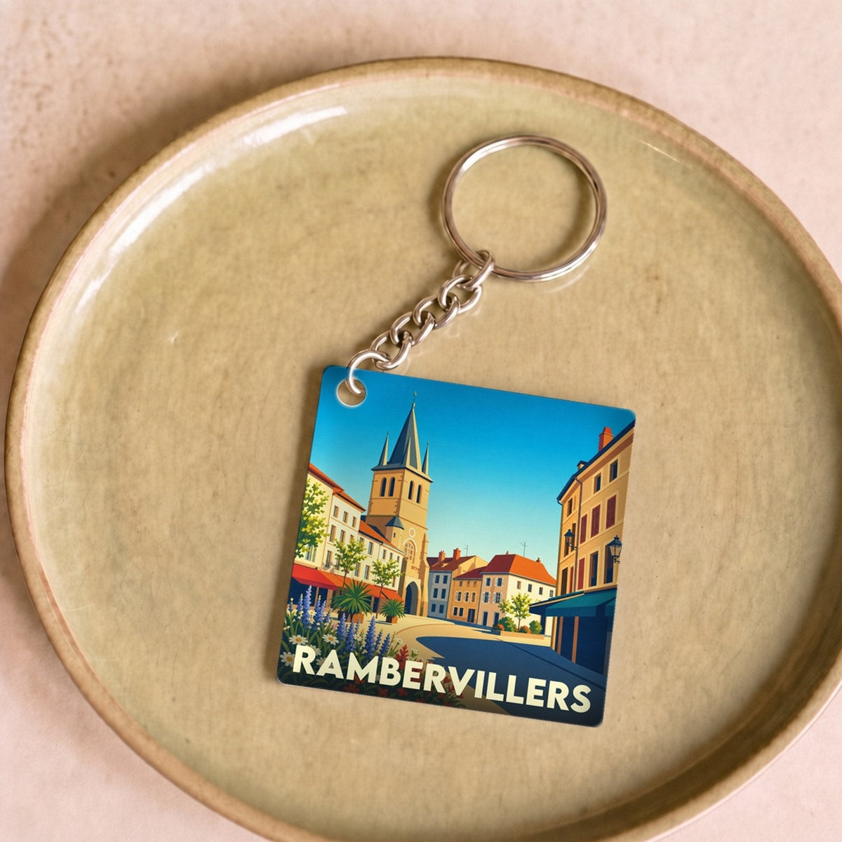 Porte-clés souvenir de la ville de Rambervillers avec une illustration stylisée.