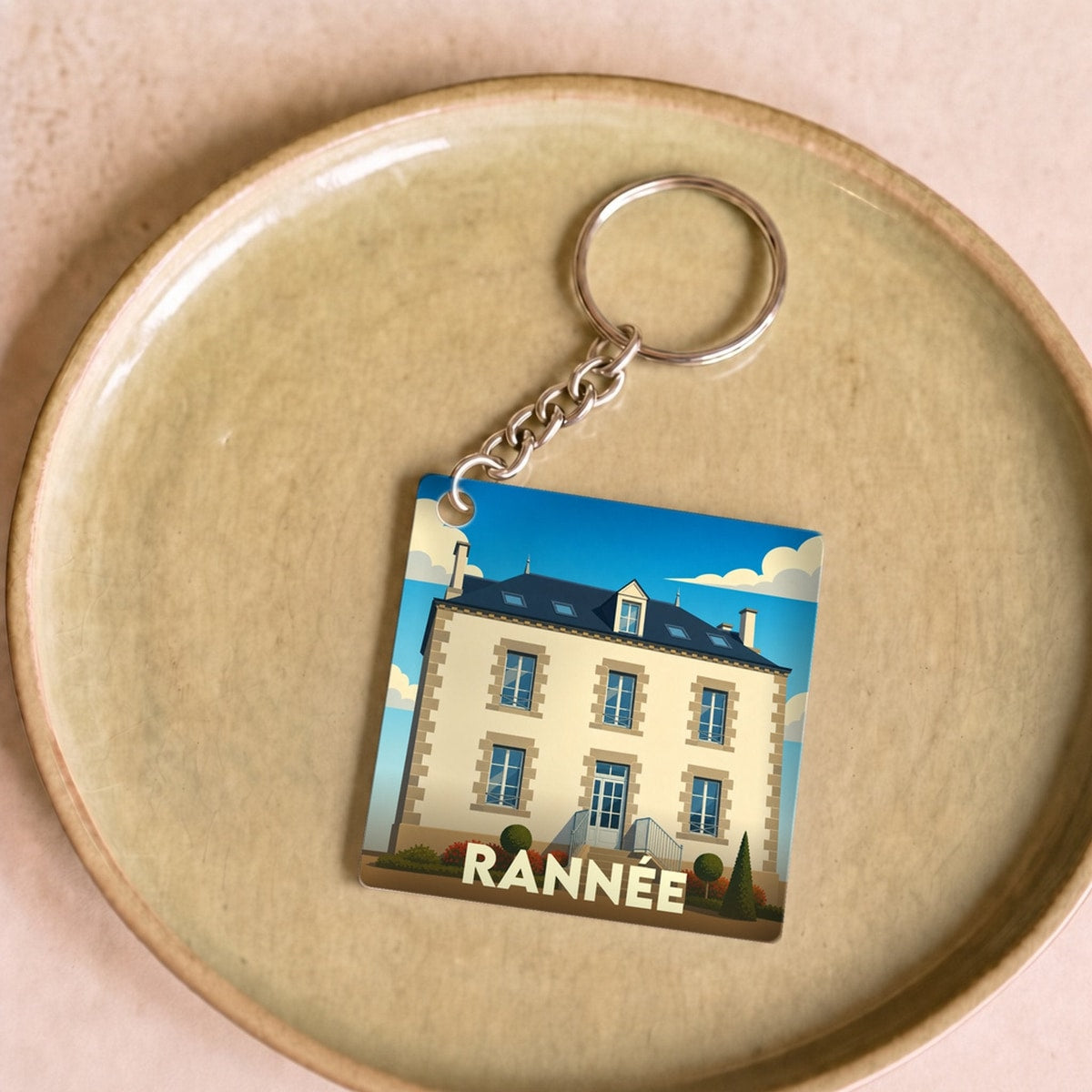Porte-clés souvenir de la ville de Rannée avec une illustration stylisée d'une maison bourgeoise.