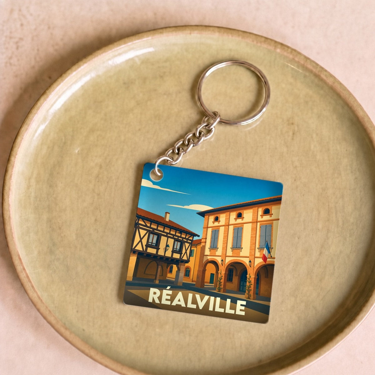 Porte-clés souvenir de la ville de Réalville avec une illustration stylisée.