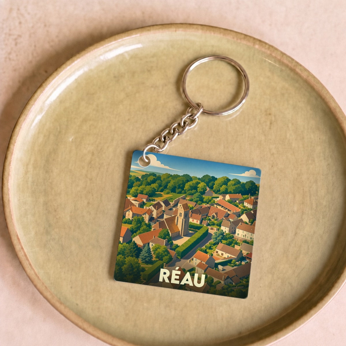 Porte-clés souvenir de la ville de Réau avec une illustration stylisée vue du ciel.