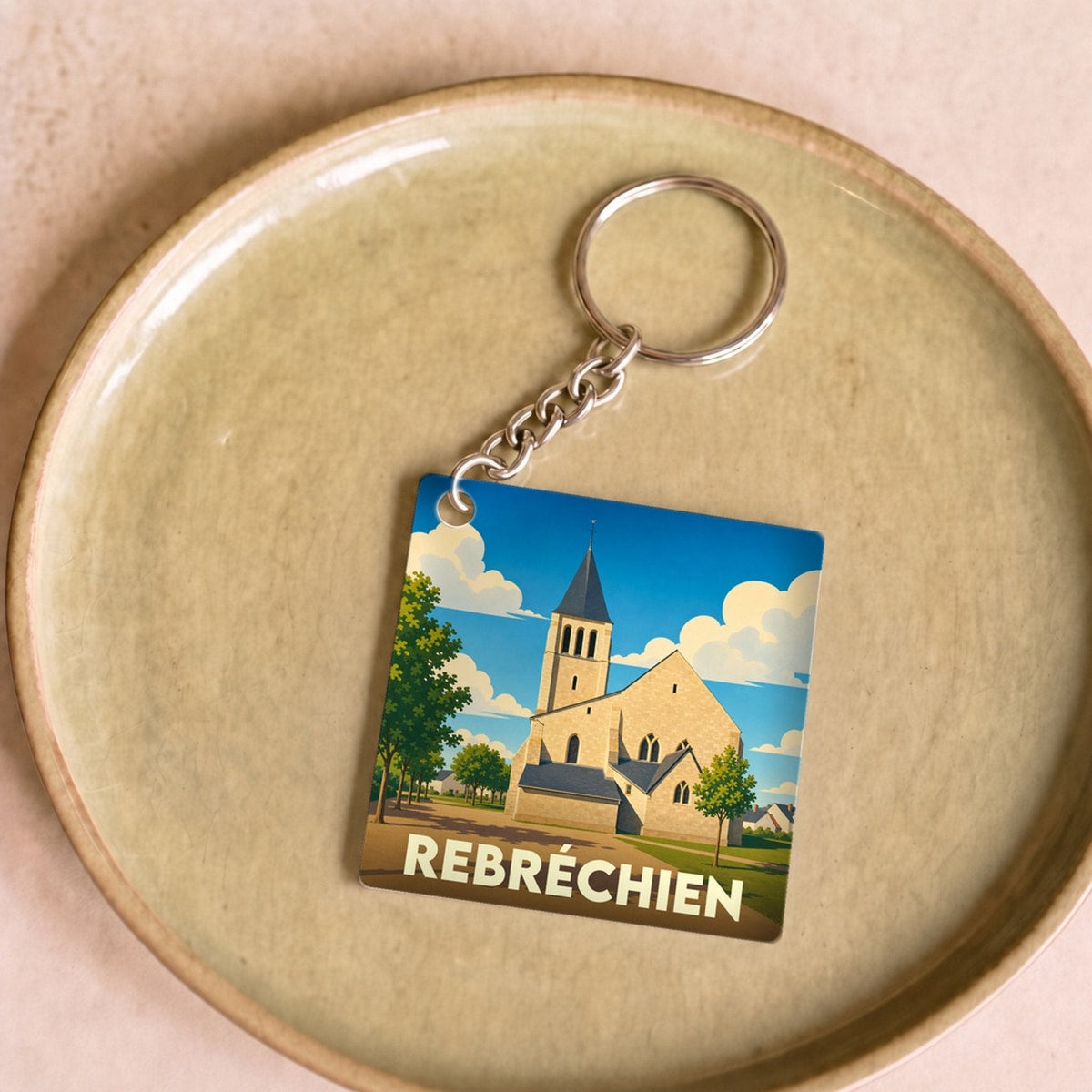 Porte-clés souvenir de la ville de Rebréchien avec une illustration stylisée de son église.