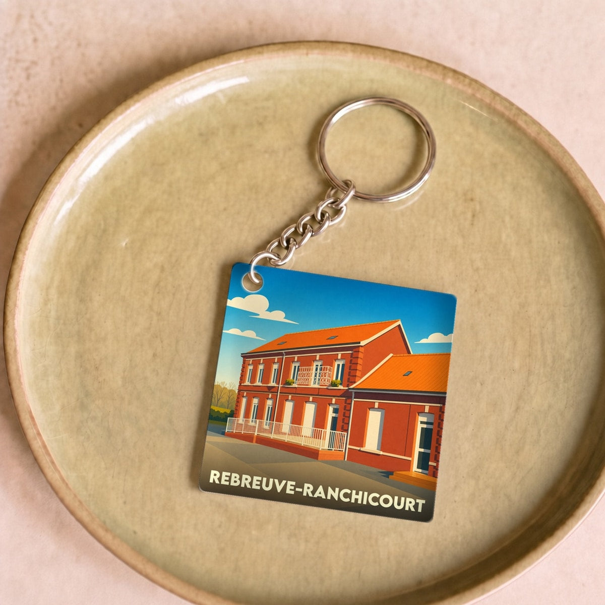 Porte-clés souvenir de la ville de Rebreuve-Ranchicourt avec une illustration stylisée.