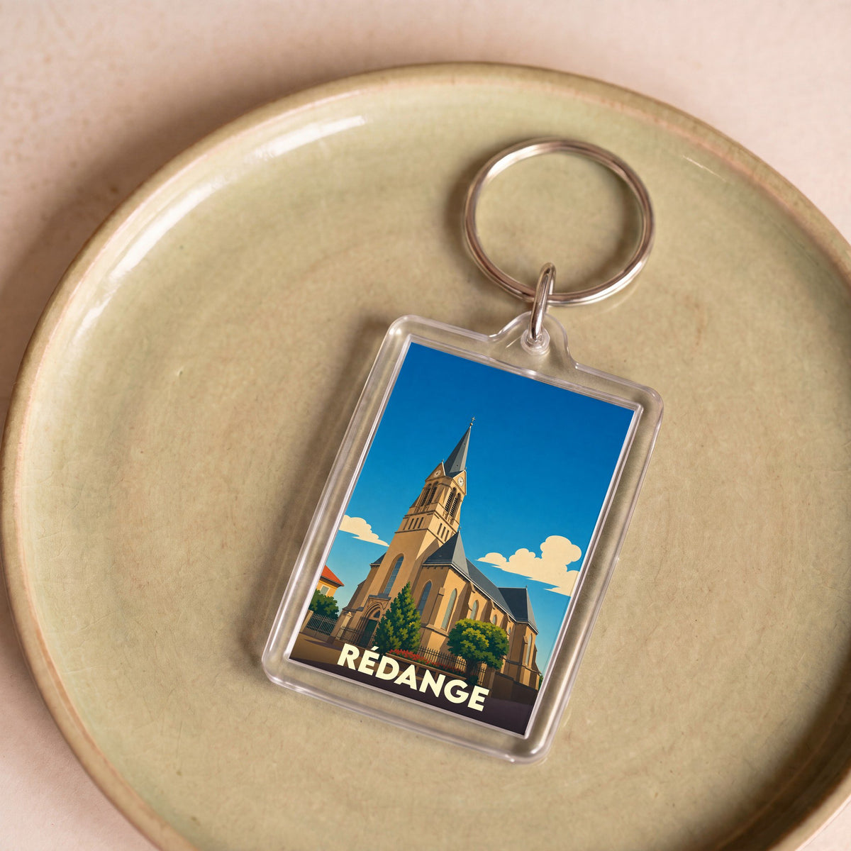 Porte-clés souvenir de la ville de Rédange avec une illustration stylisée de son église.
