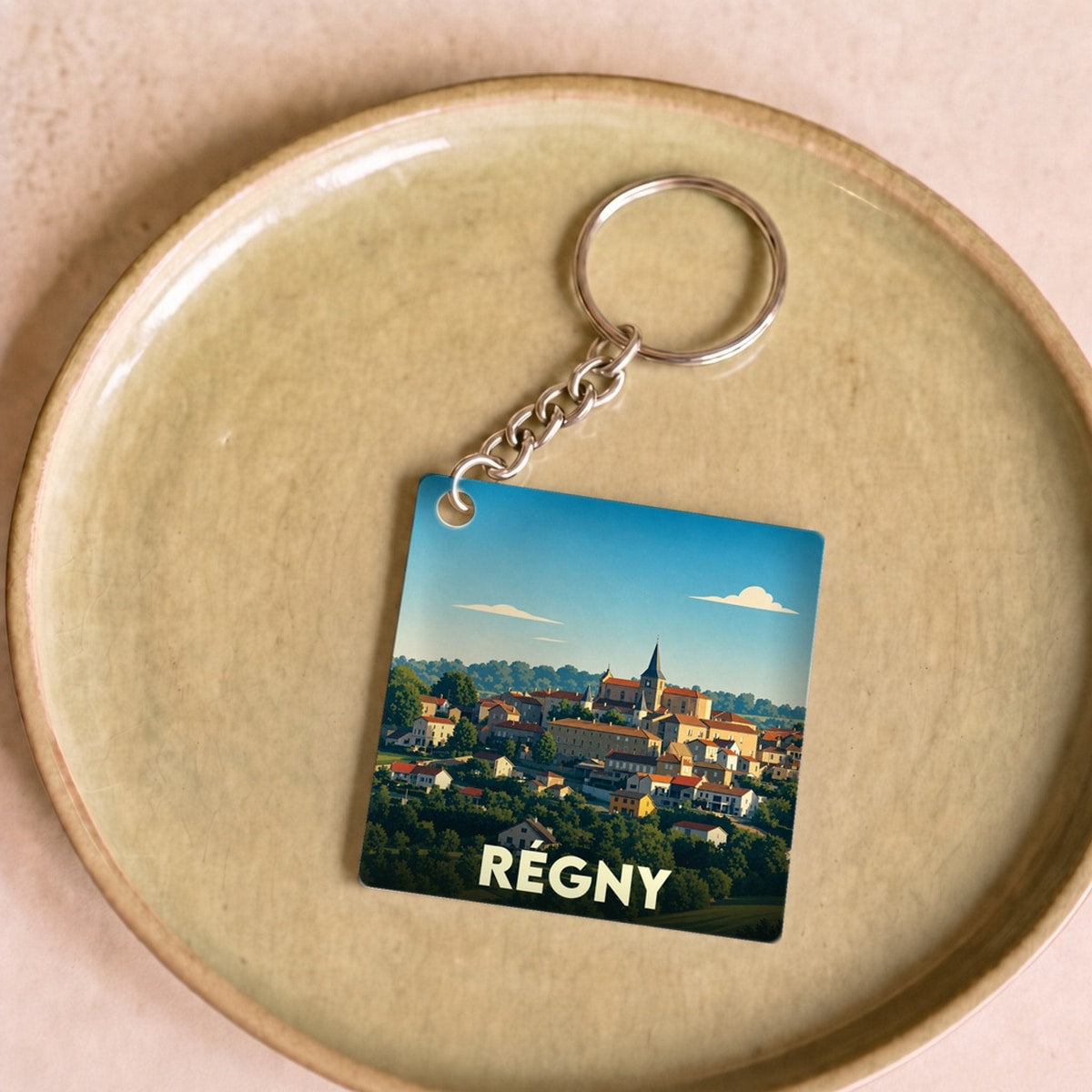 Porte-clés souvenir de la ville de Régny avec une illustration stylisée.