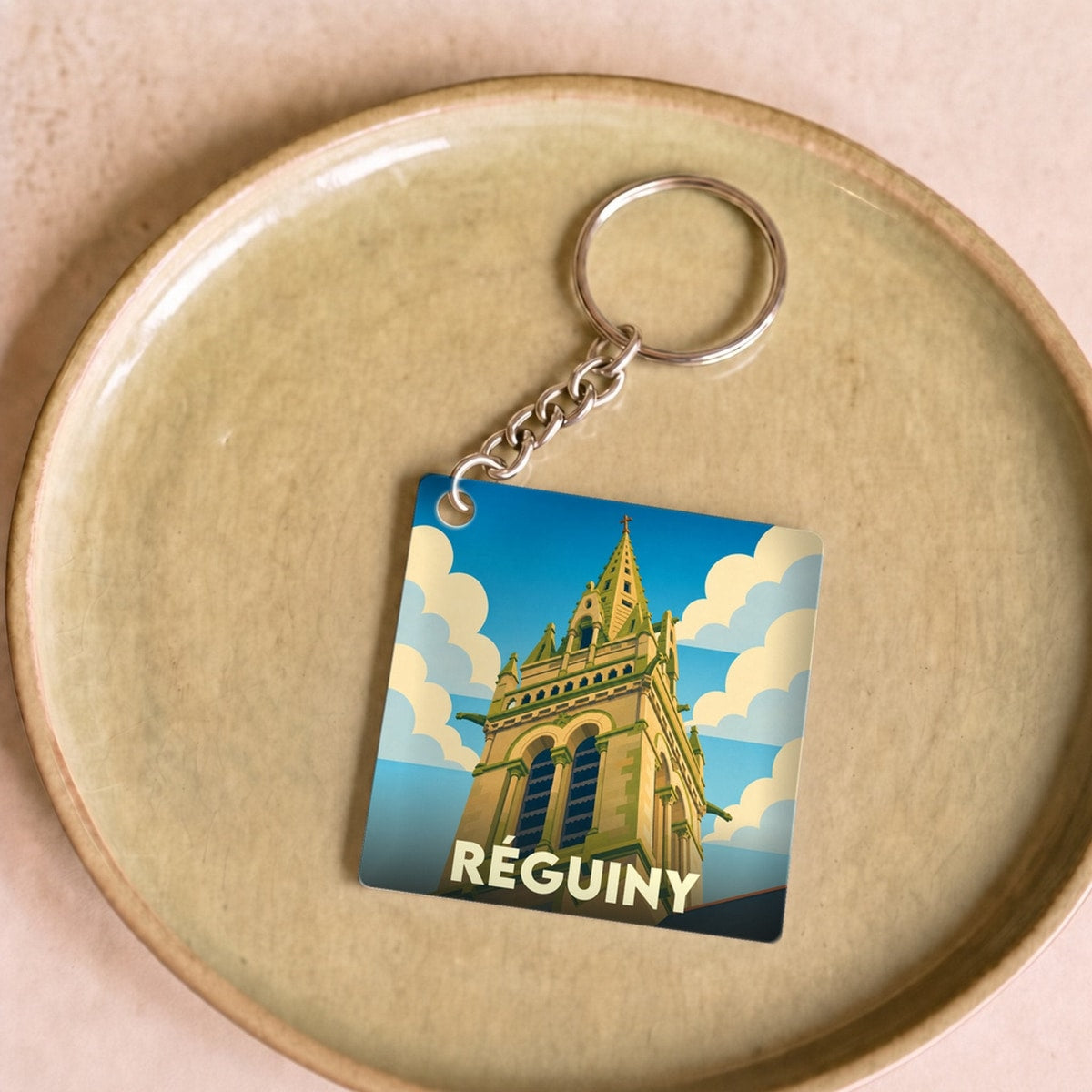 Porte-clés souvenir de la ville de Réguiny avec une illustration stylisée d'un clocher.