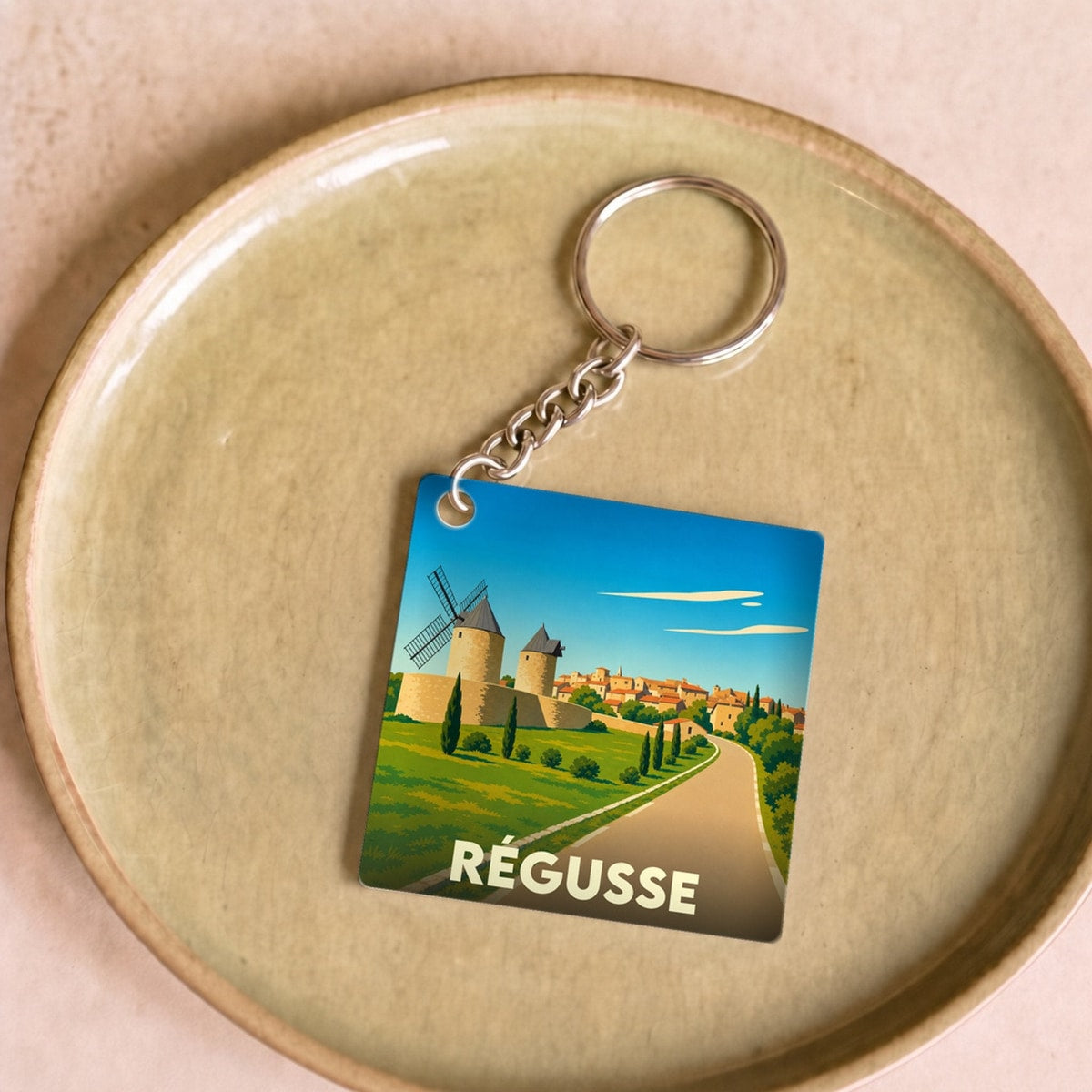 Porte-clés souvenir de la ville de Régusse avec une illustration stylisée de ses moulins.