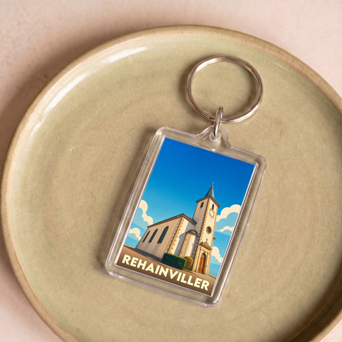 Porte-clés souvenir de la ville de Rehainviller avec une illustration stylisée de son église.