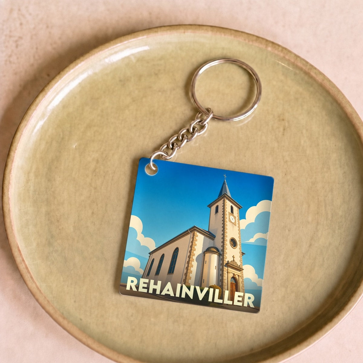 Porte-clés souvenir de la ville de Rehainviller avec une illustration stylisée de son église.