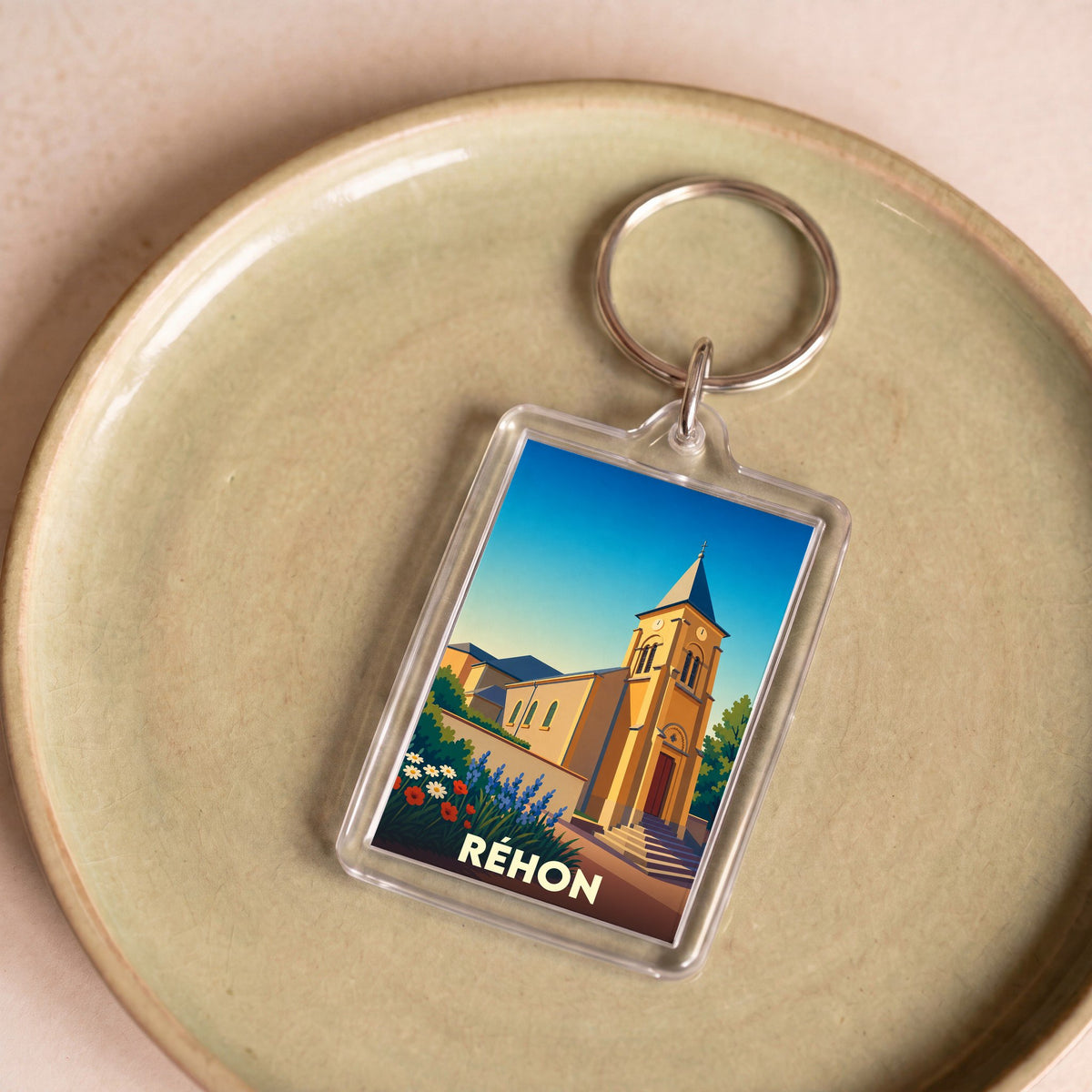 Porte-clés souvenir de la ville de Réhon avec une illustration stylisée de son église.