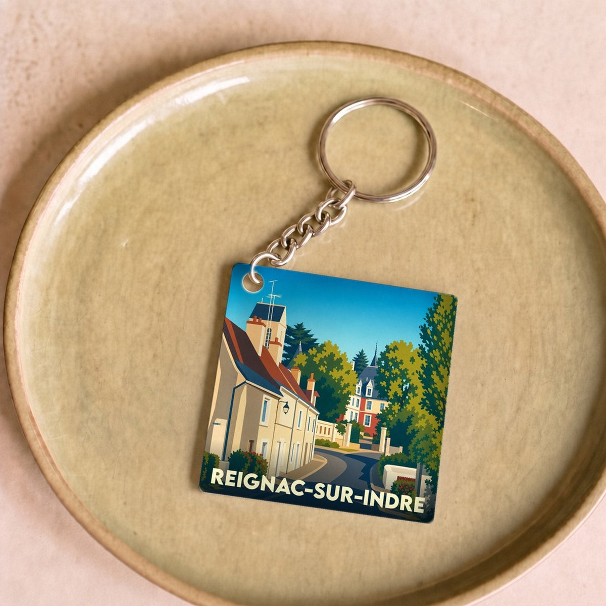 Porte-clés souvenir de la ville de Reignac-sur-Indre avec une illustration stylisée.
