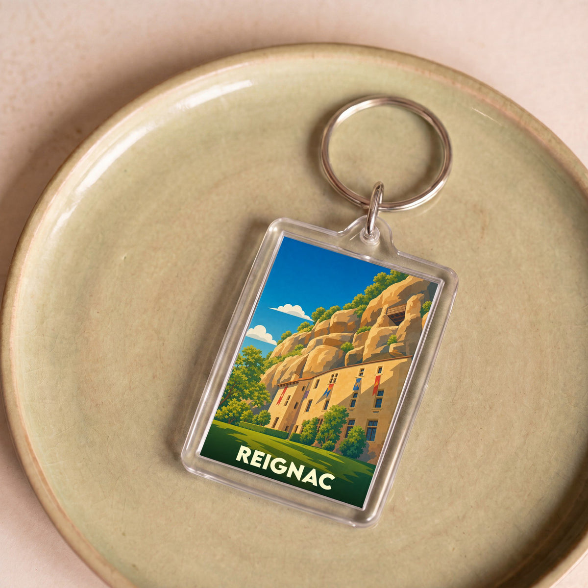 Porte-clés souvenir de la ville de Reignac avec une illustration stylisée.