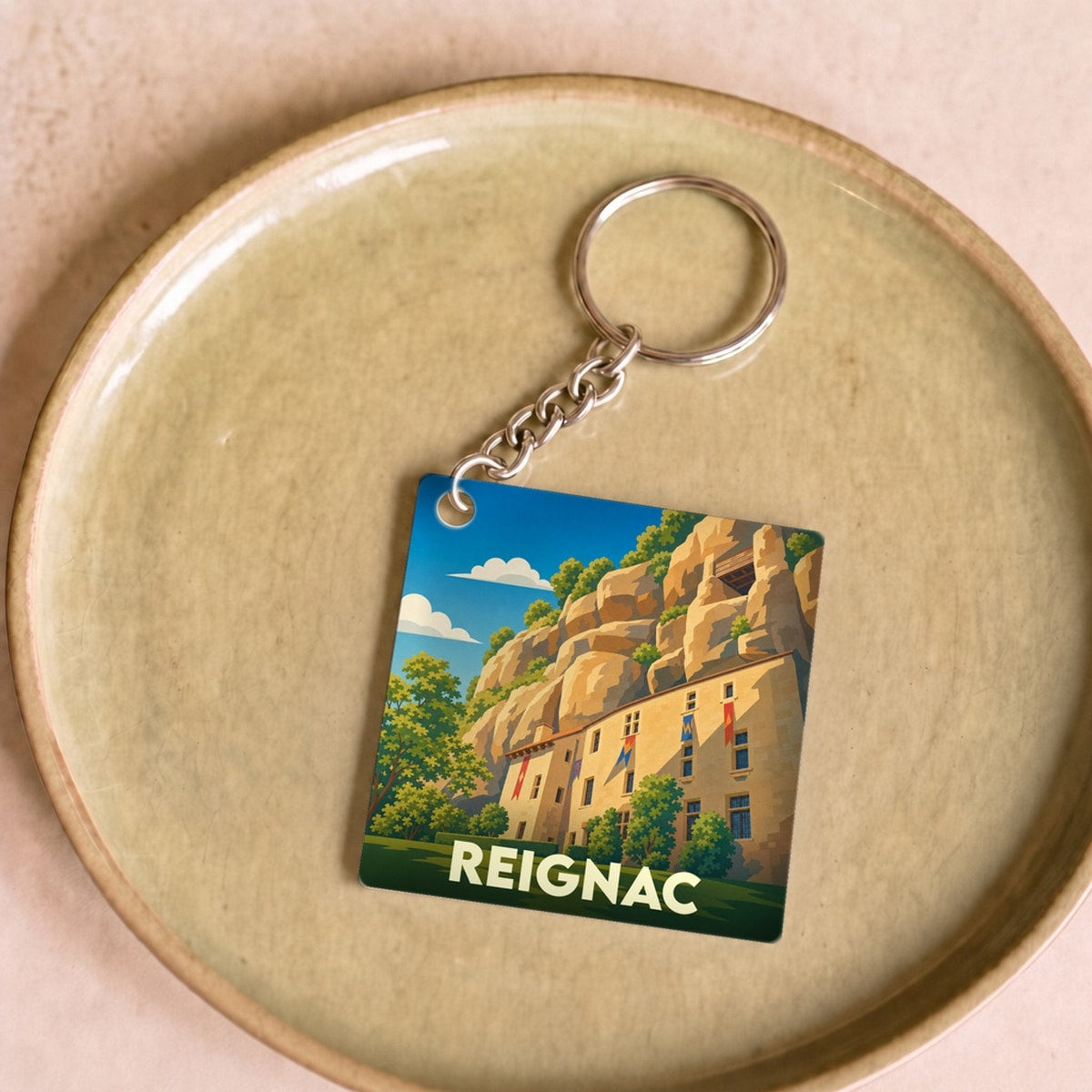 Porte-clés souvenir de la ville de Reignac avec une illustration stylisée.