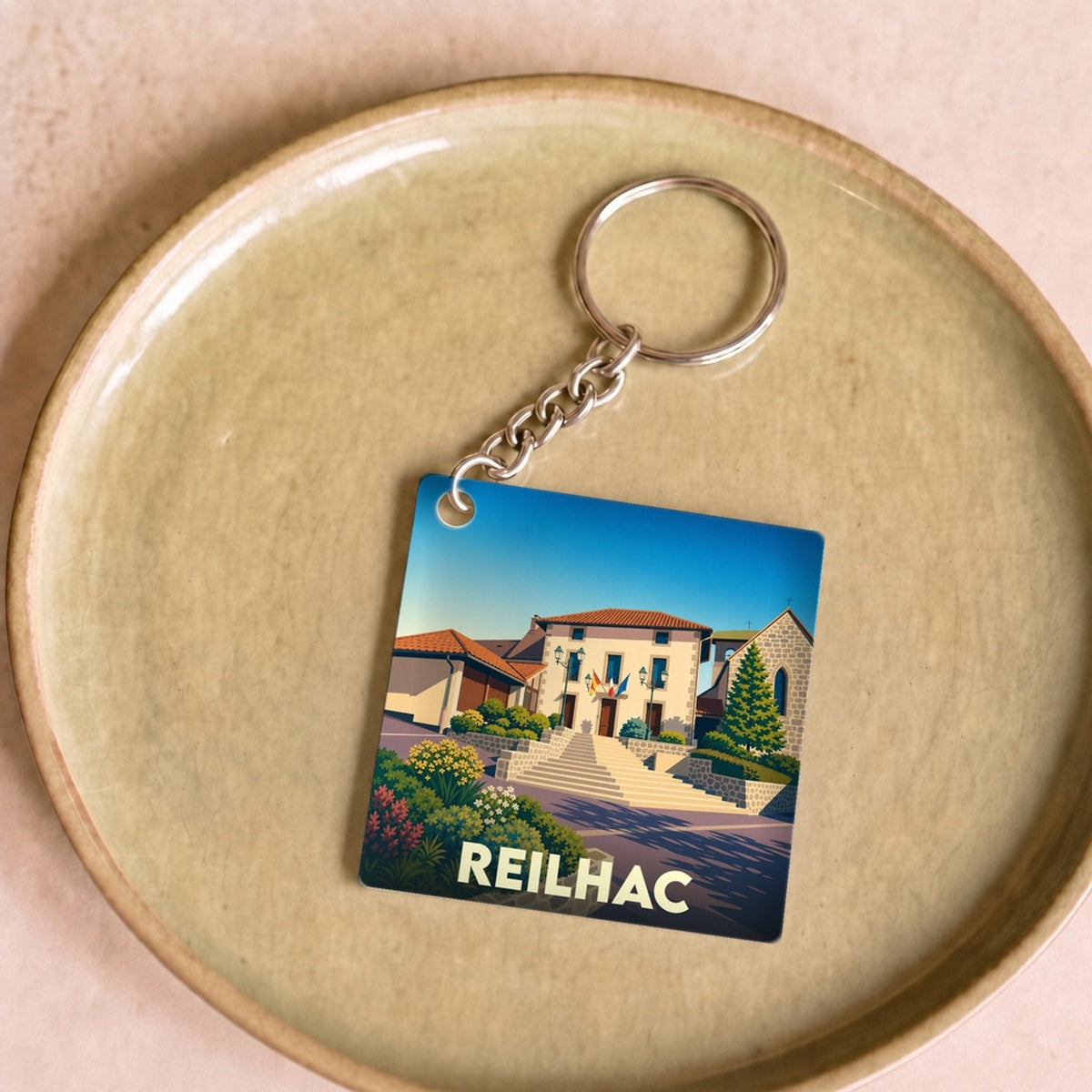 Porte-clés souvenir de la ville de Reilhac avec une illustration stylisée.