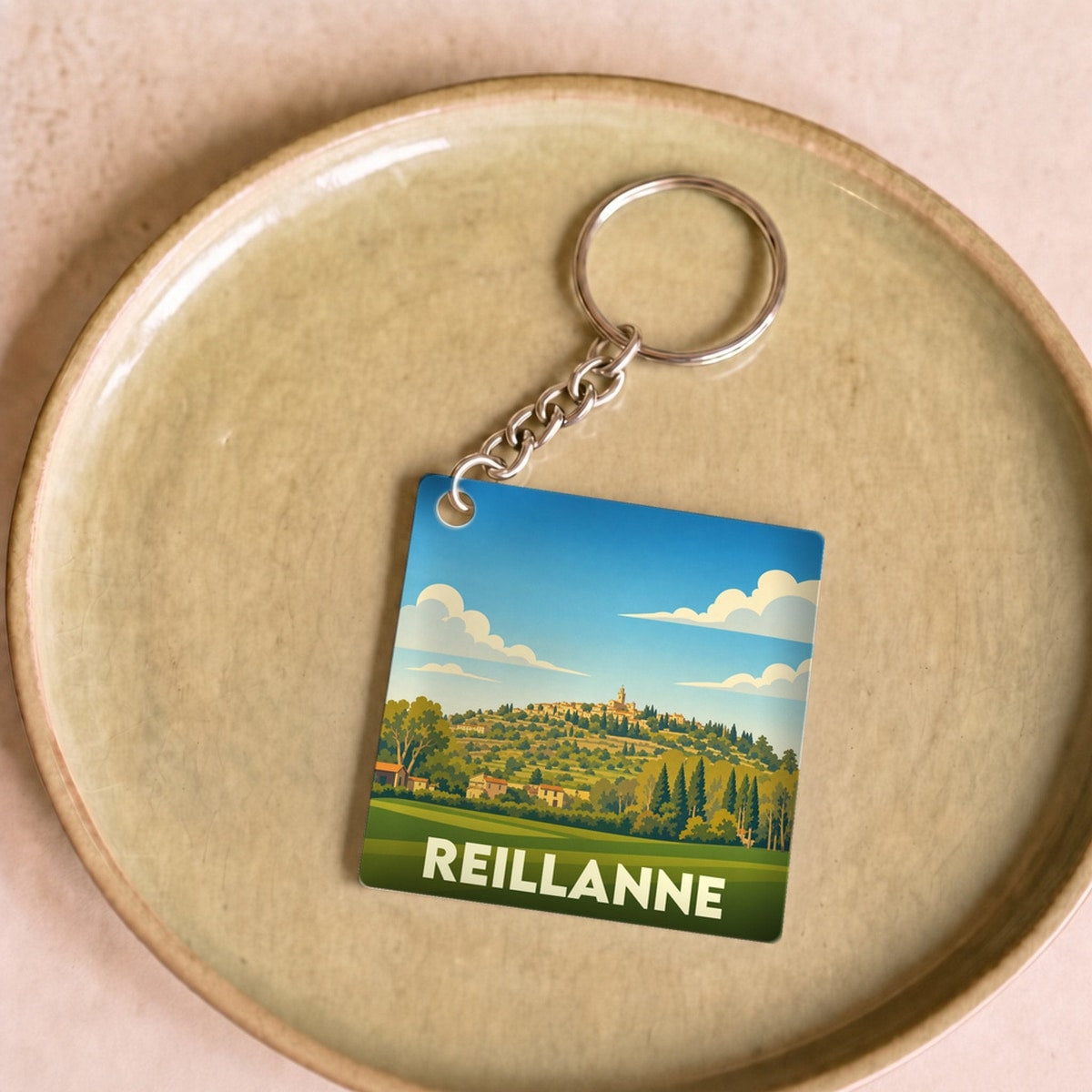 Porte-clés souvenir de la ville de Reillanne avec une illustration stylisée.