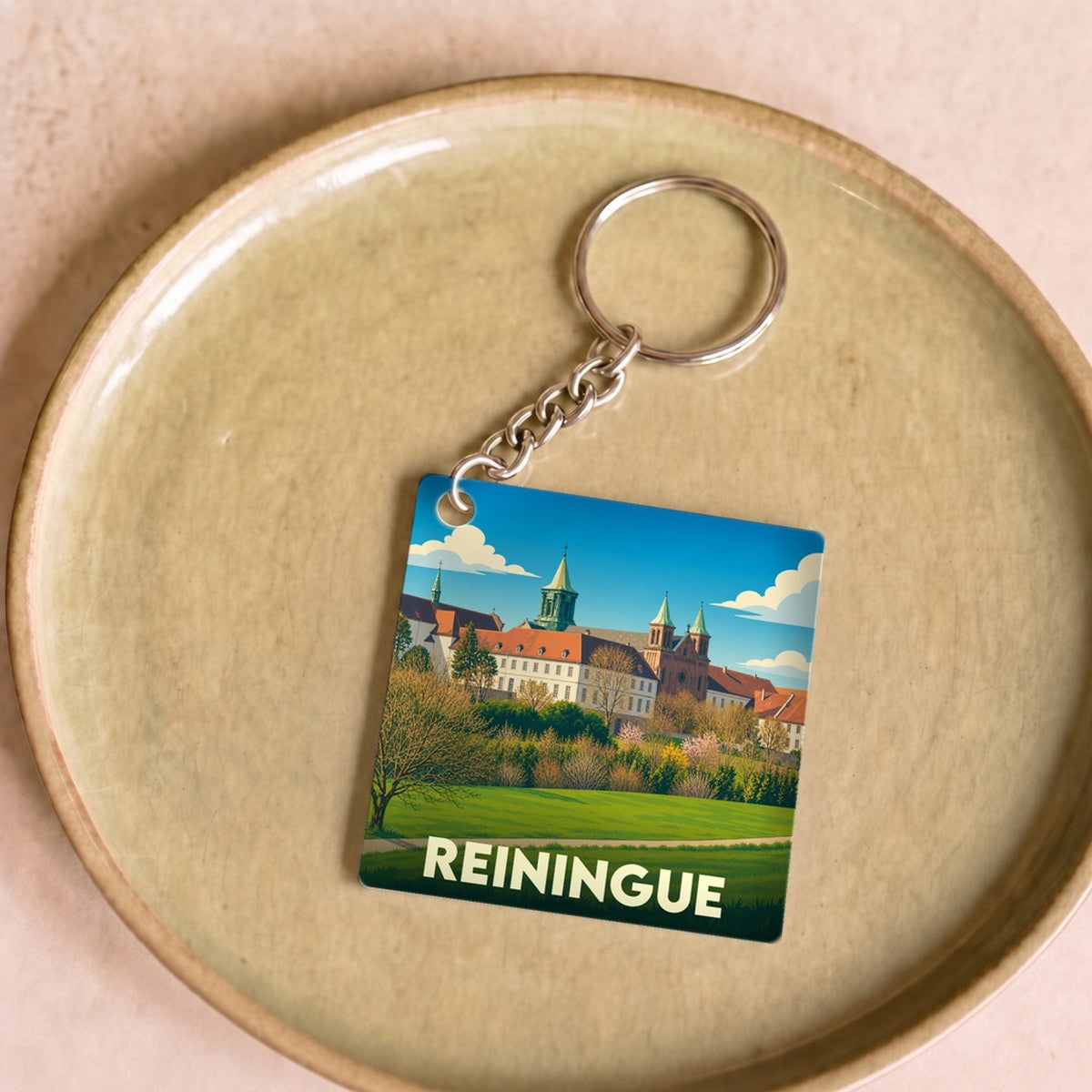 Porte-clés souvenir de la ville de Reiningue avec une illustration stylisée de son abbaye.
