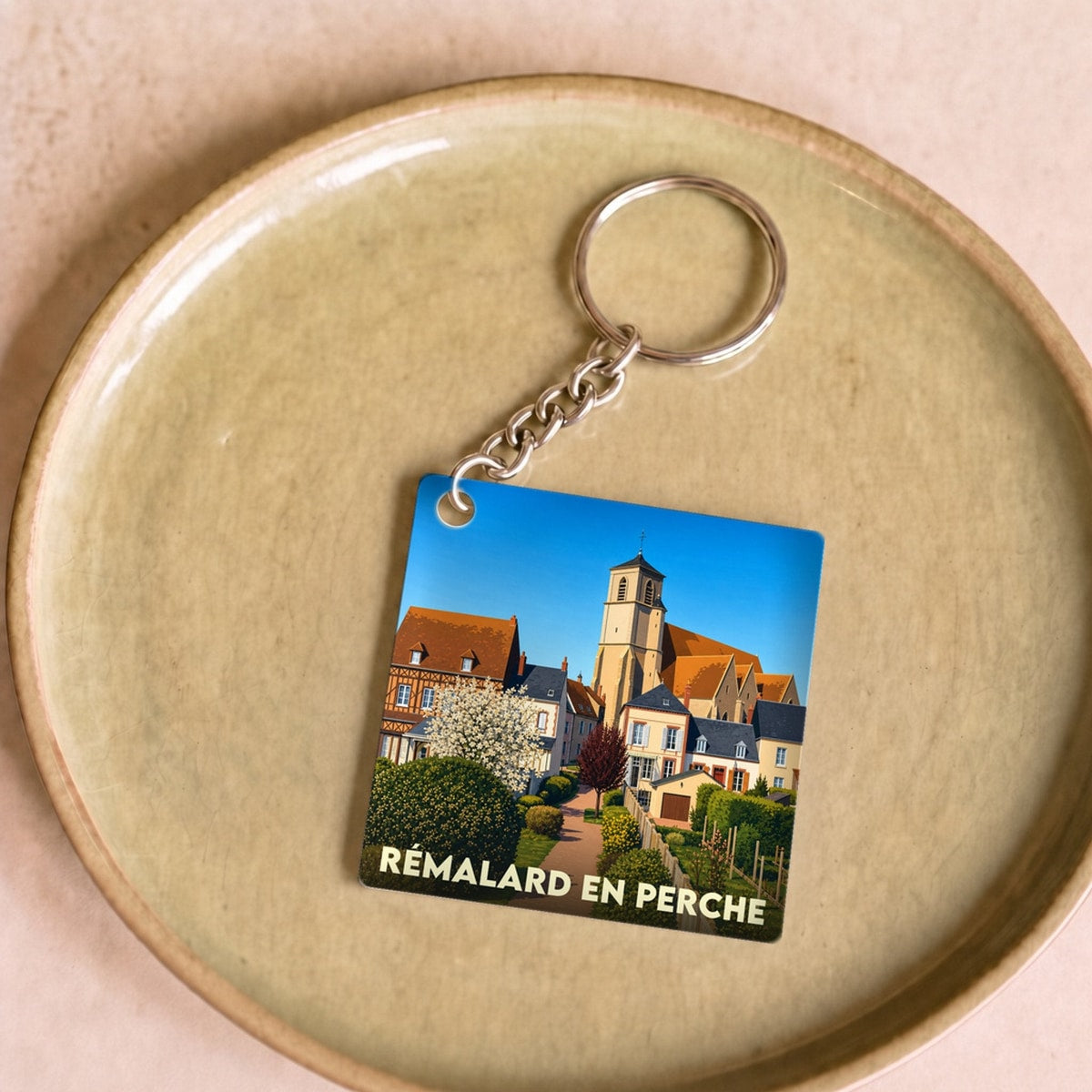 Porte-clés souvenir de la ville de Rémalard en Perche avec une illustration stylisée.