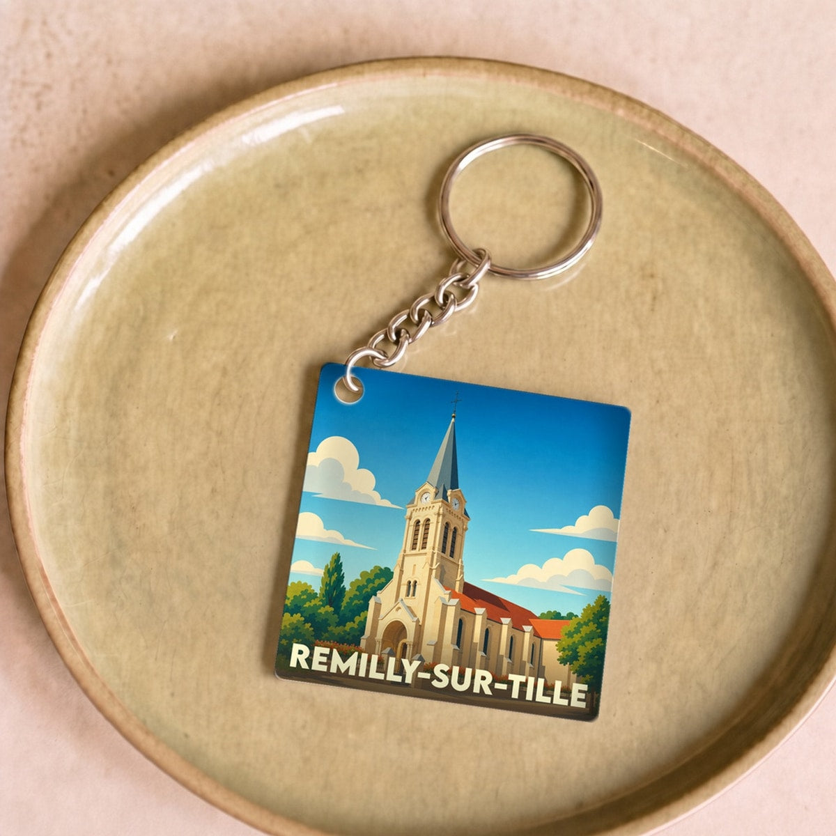 Porte-clés souvenir de la ville de Remilly-sur-Tille avec une illustration stylisée de son église.