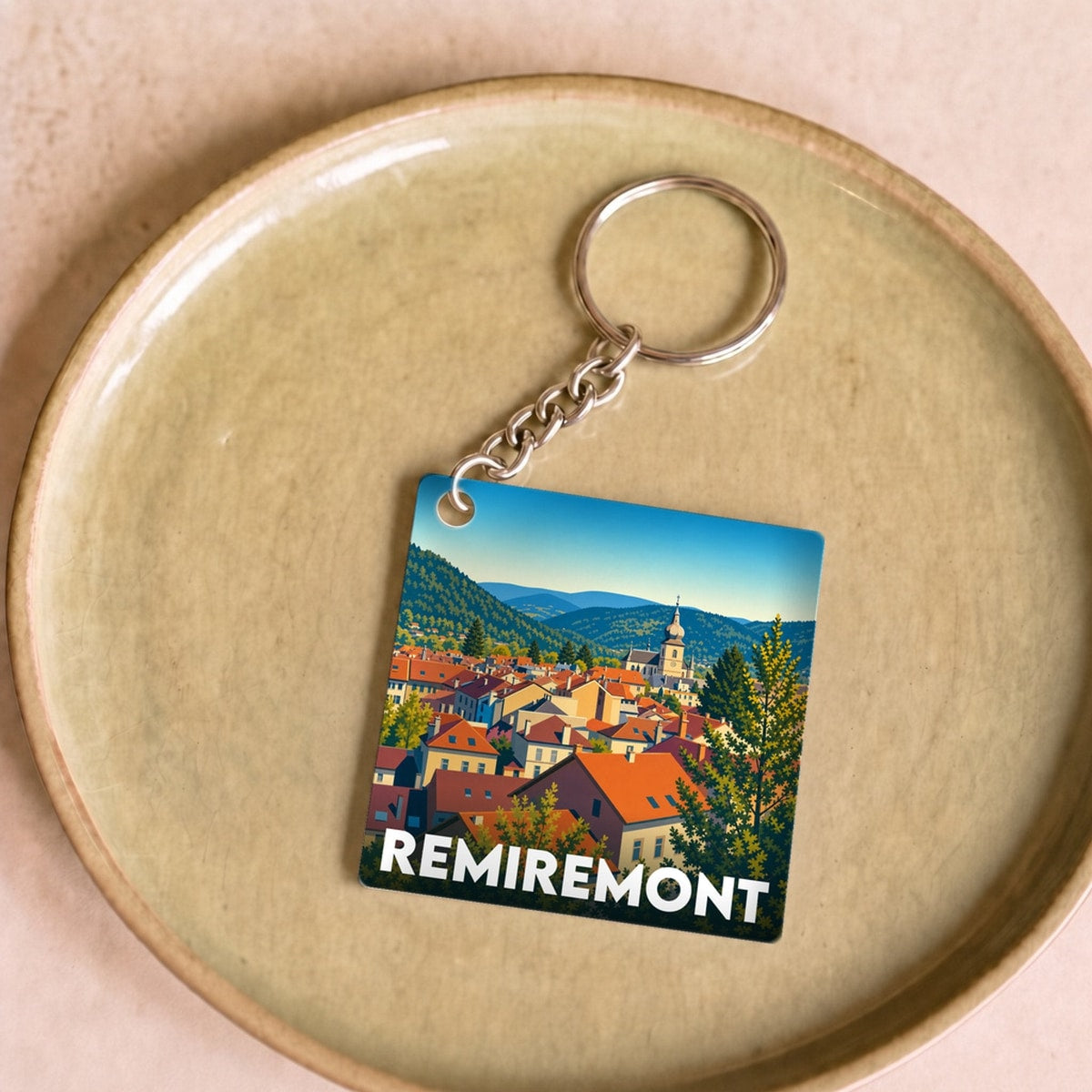 Porte-clés souvenir de la ville de Remiremont avec une illustration stylisée.