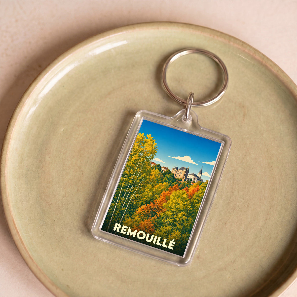 Porte-clés souvenir de la ville de Remouillé avec une illustration stylisée d'un paysage d'automne.