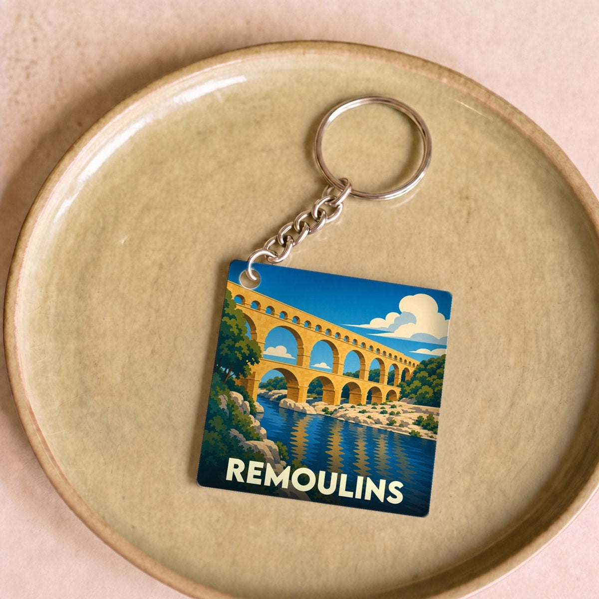 Porte-clés souvenir de la ville de Remoulins avec une illustration stylisée du Pont du Gard.