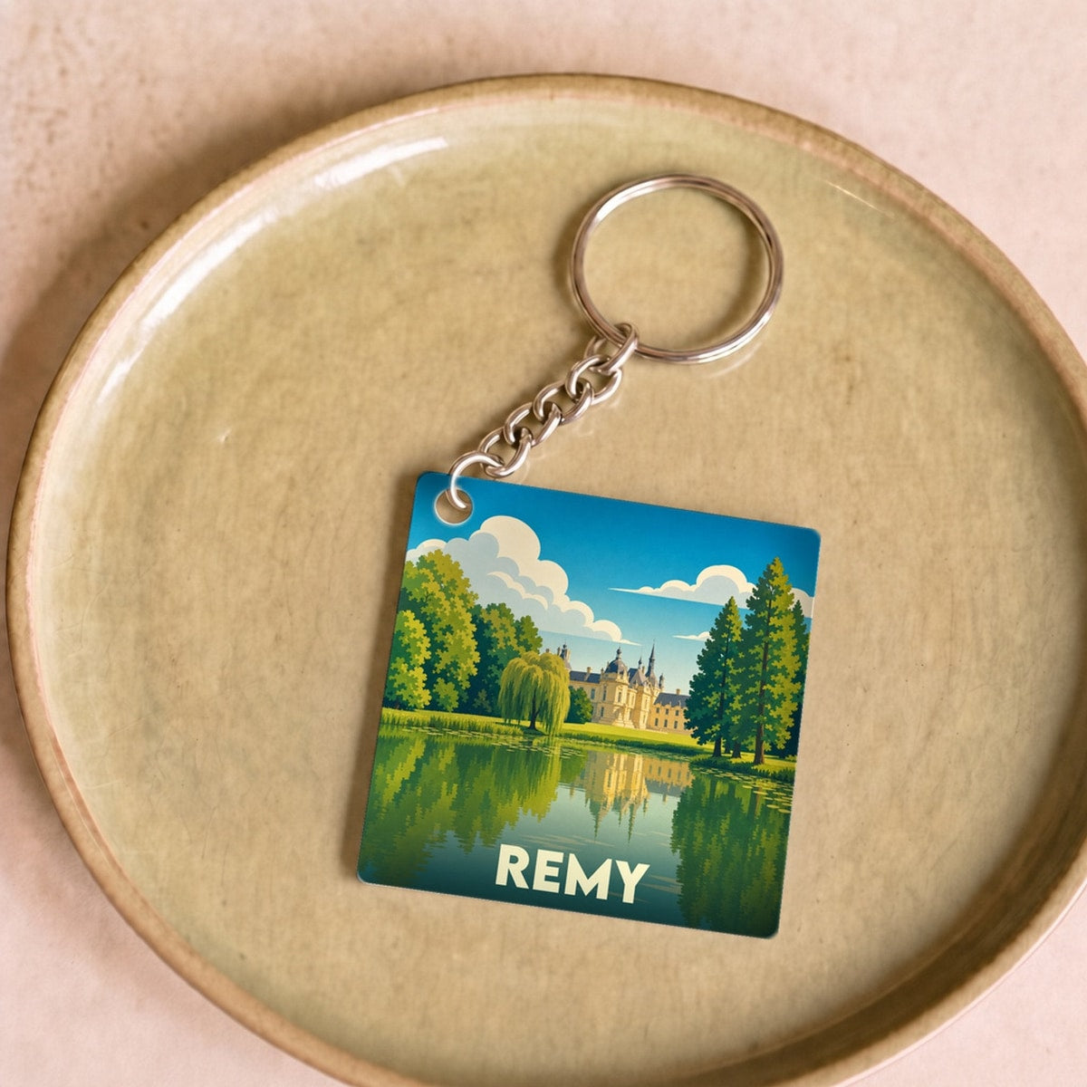 Porte-clés souvenir de la ville de Remy avec une illustration stylisée d'un château se reflétant dans l'eau.