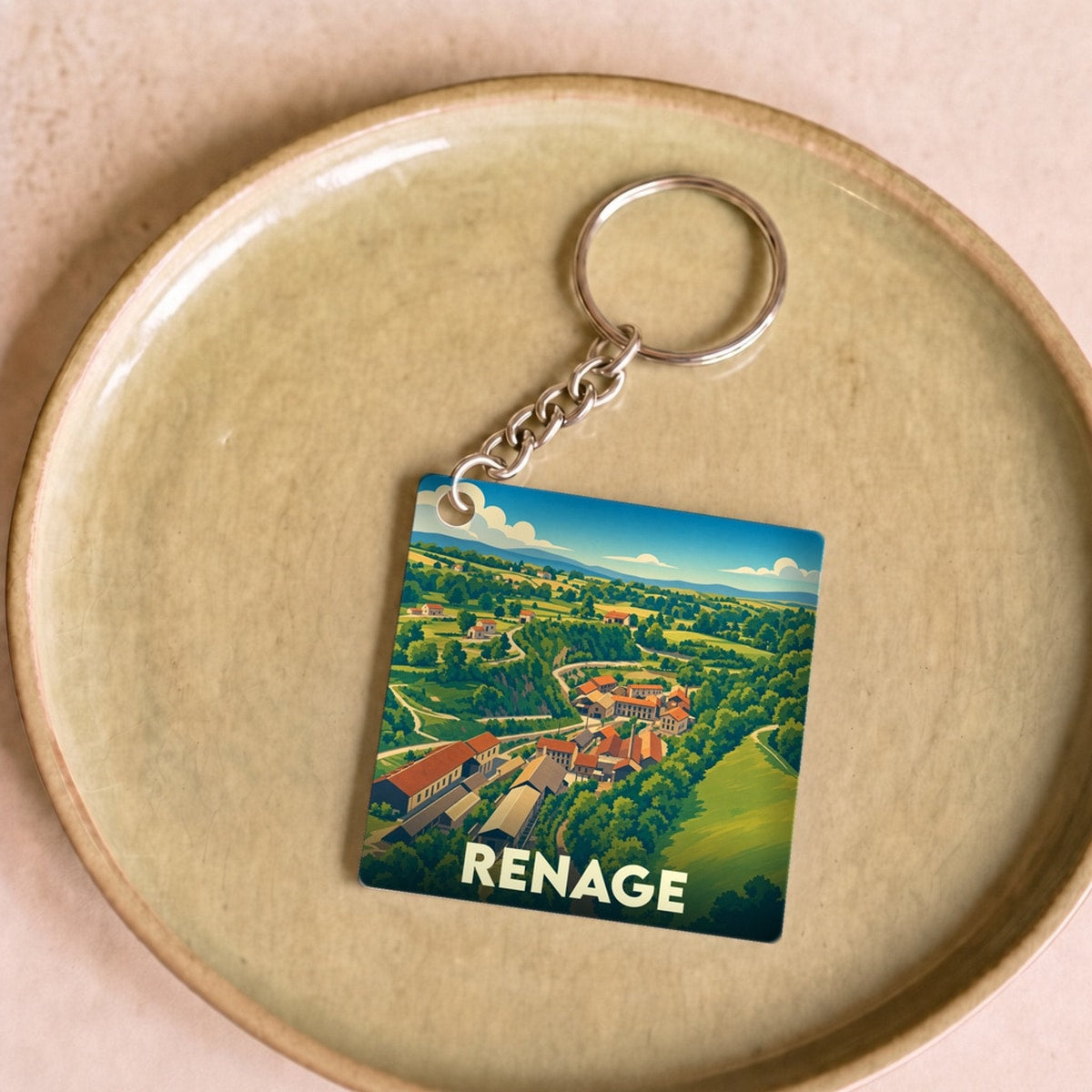 Porte-clés souvenir de la ville de Renage avec une illustration stylisée de son paysage rural.