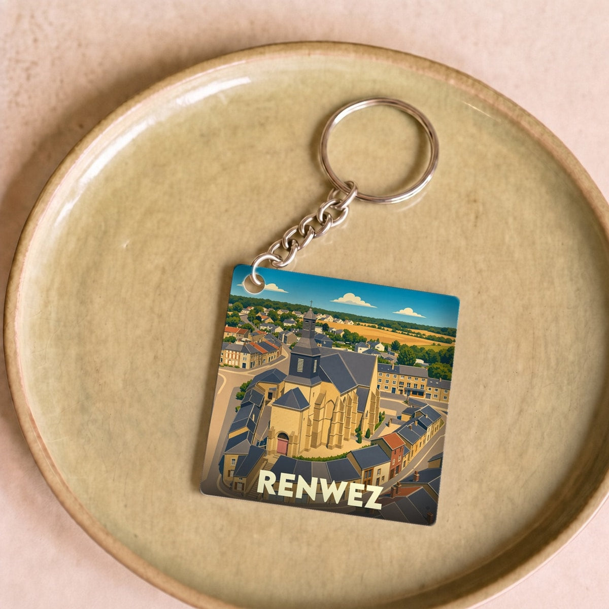 Porte-clés souvenir de la ville de Renwez avec une illustration stylisée de son église et de ses environs.
