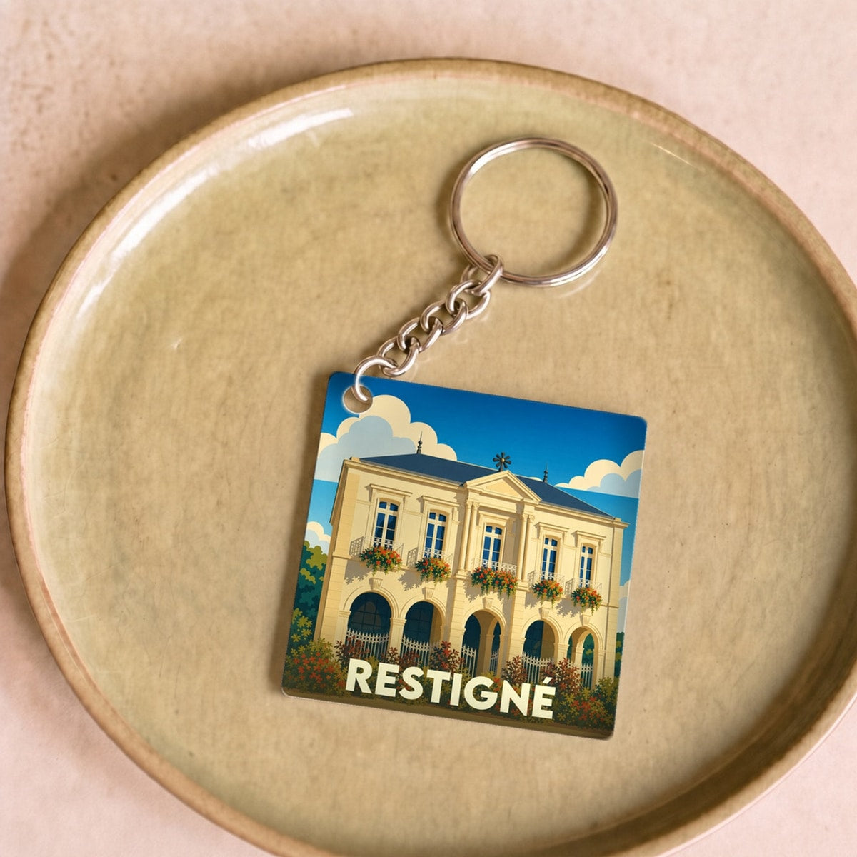 Porte-clés souvenir de la ville de Restigné avec une illustration stylisée d'un bâtiment historique.