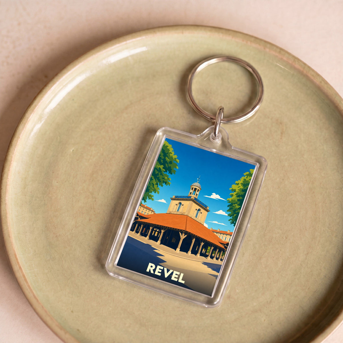 Porte-clés souvenir de la ville de Revel avec une illustration stylisée de sa halle centrale.