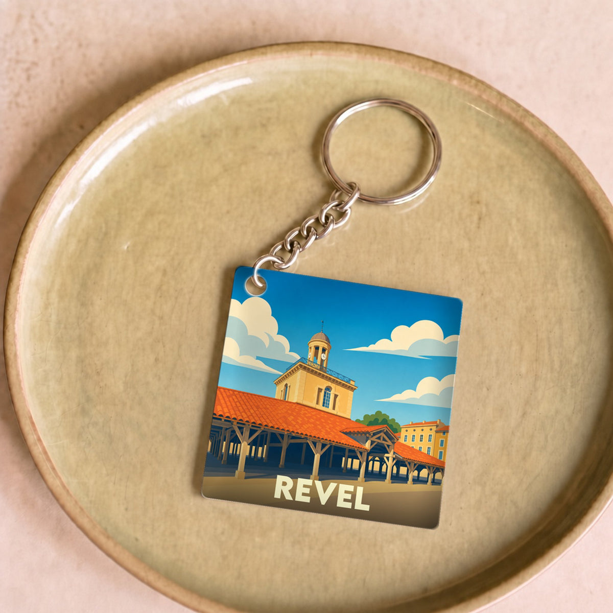 Porte-clés souvenir de la ville de Revel avec une illustration stylisée de sa halle centrale.