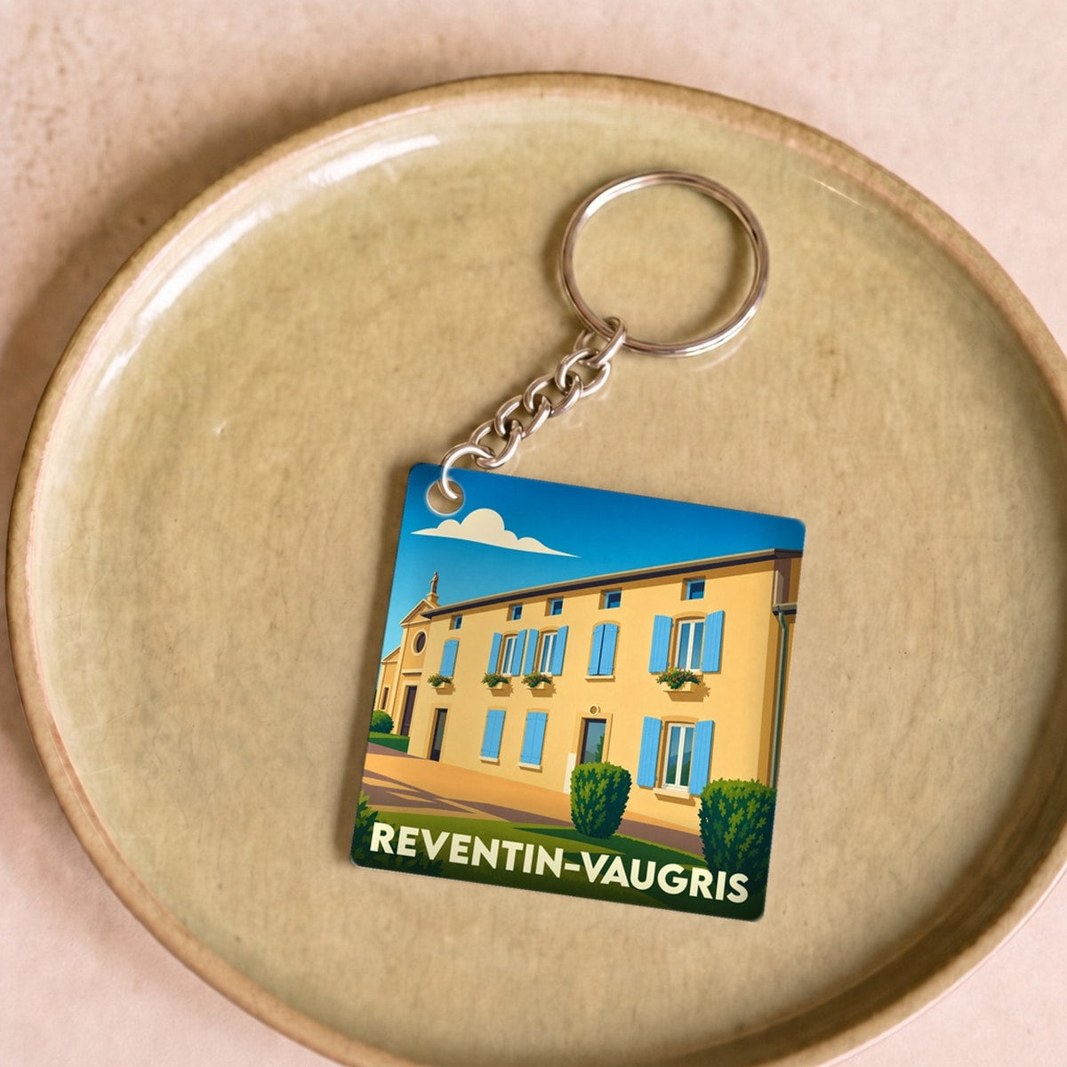 Porte-clés souvenir de la ville de Reventin-Vaugris avec une illustration stylisée.