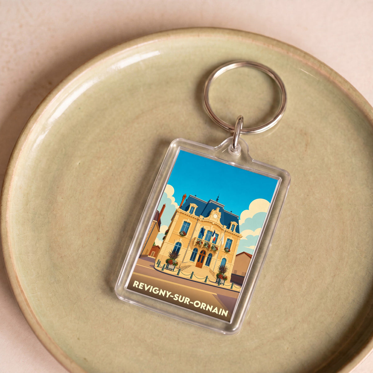 Porte-clés souvenir de la ville de Revigny-sur-Ornain avec une illustration stylisée de son hôtel de ville.