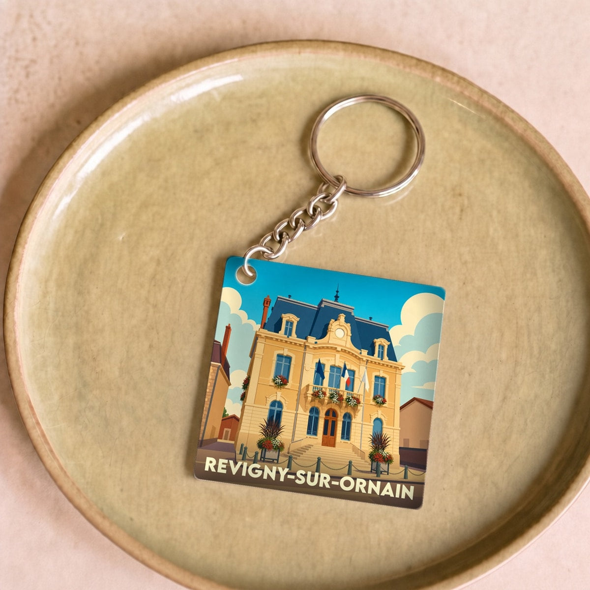 Porte-clés souvenir de la ville de Revigny-sur-Ornain avec une illustration stylisée de son hôtel de ville.