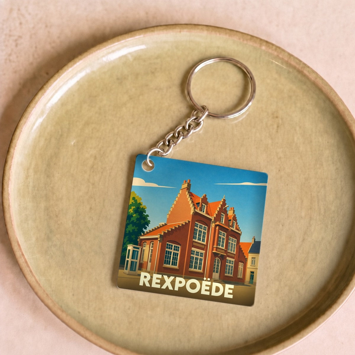 Porte-clés souvenir de la ville de Rexpoëde avec une illustration stylisée.
