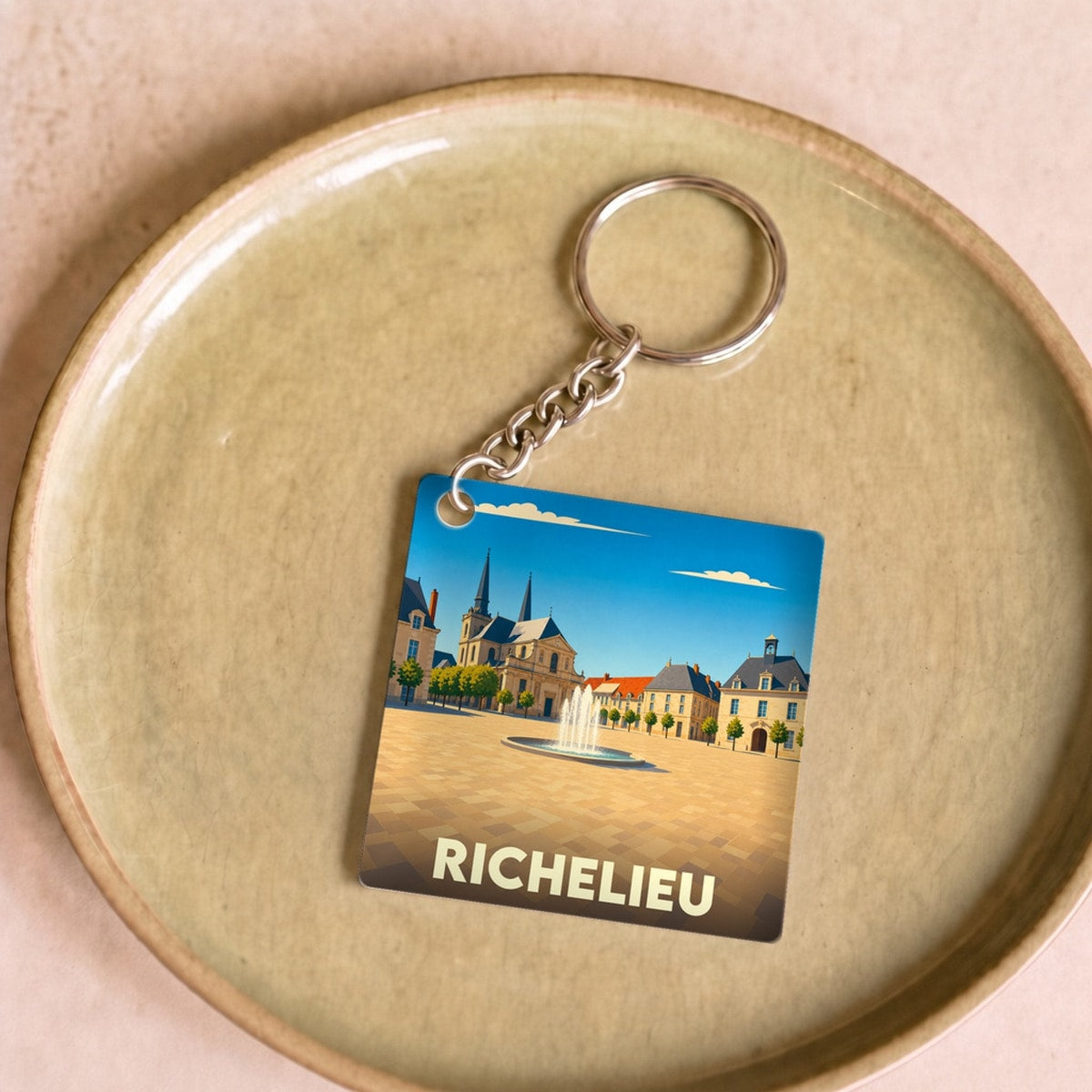 Porte-clés souvenir de la ville de Richelieu avec une illustration stylisée de sa place principale.