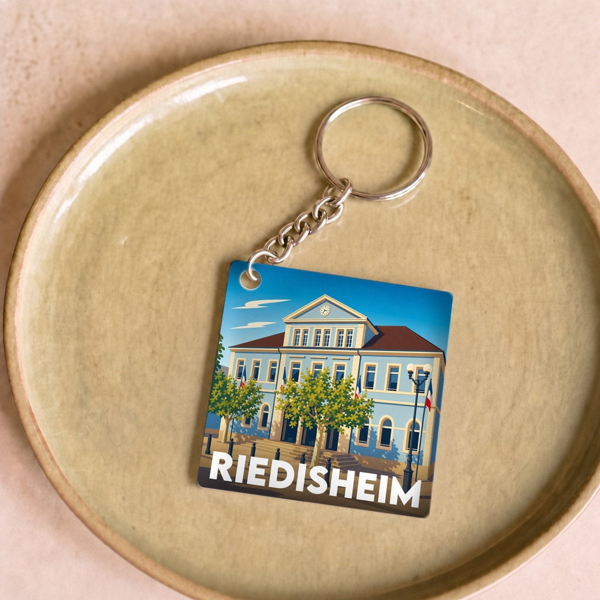 Porte-clés souvenir de la ville de Riedisheim avec une illustration stylisée de son hôtel de ville.
