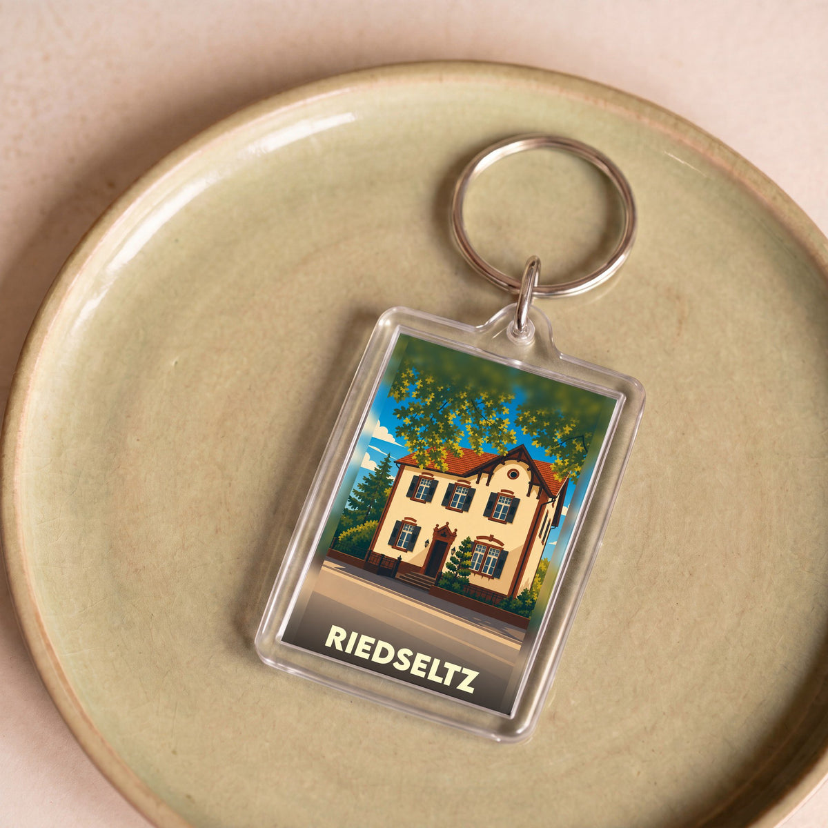 Porte-clés souvenir de la ville de Riedseltz avec une illustration stylisée d'une maison traditionnelle.