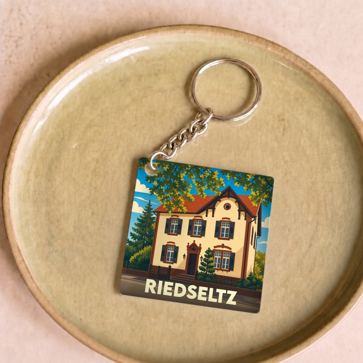 Porte-clés souvenir de la ville de Riedseltz avec une illustration stylisée d'une maison traditionnelle.