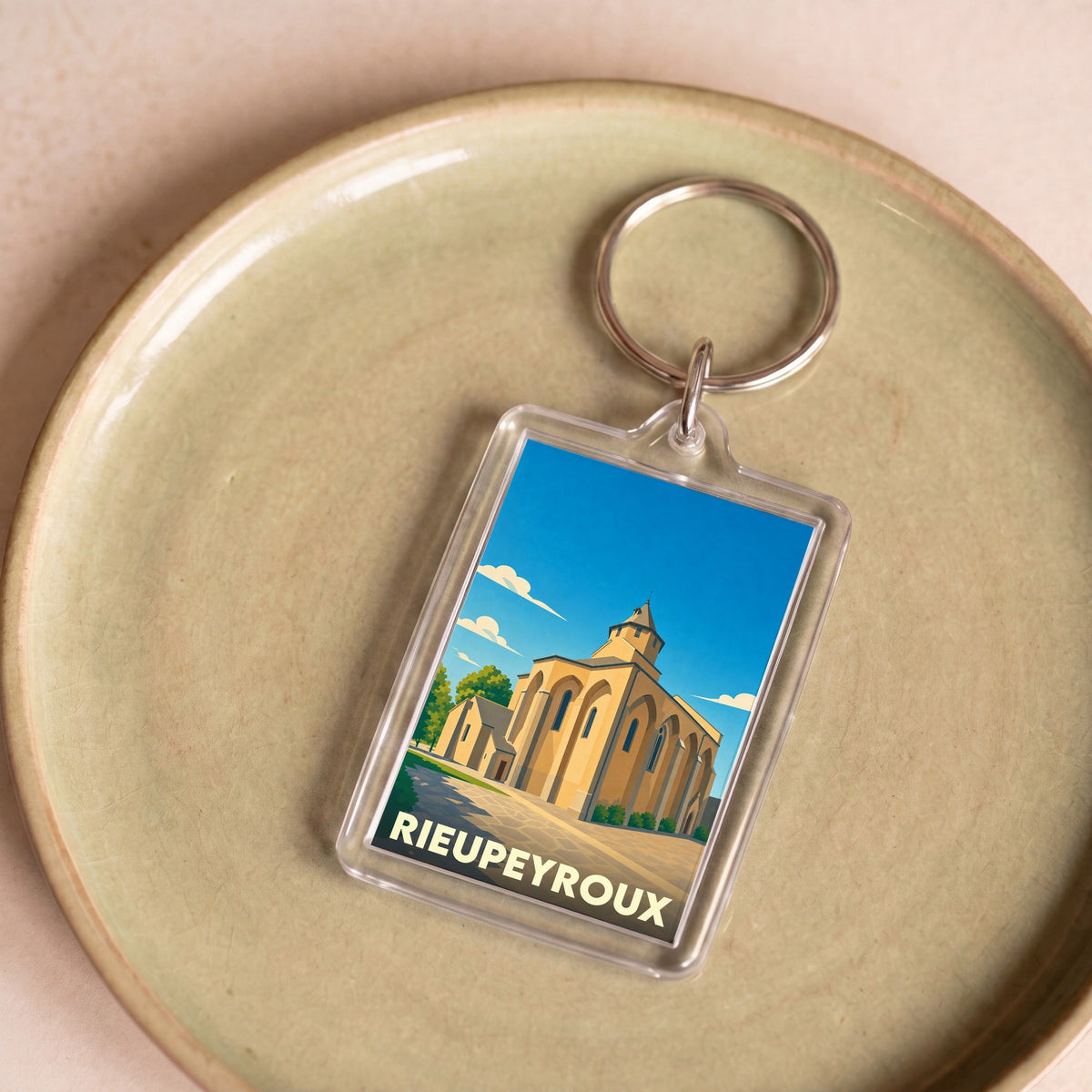 Porte-clés souvenir de la ville de Rieupeyroux avec une illustration stylisée de son église.