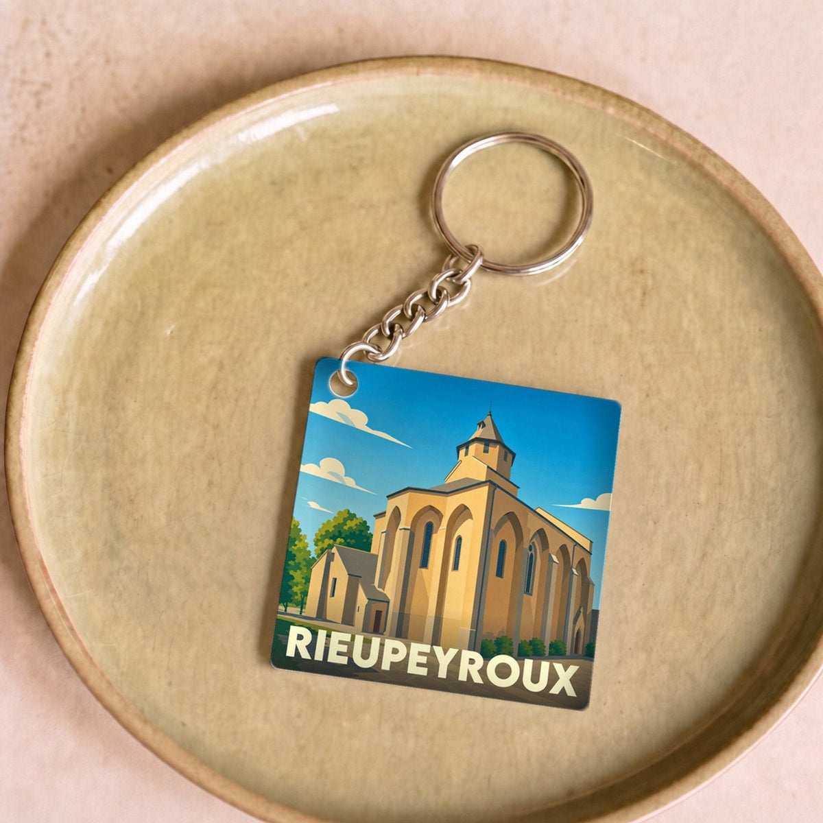 Porte-clés souvenir de la ville de Rieupeyroux avec une illustration stylisée de son église.