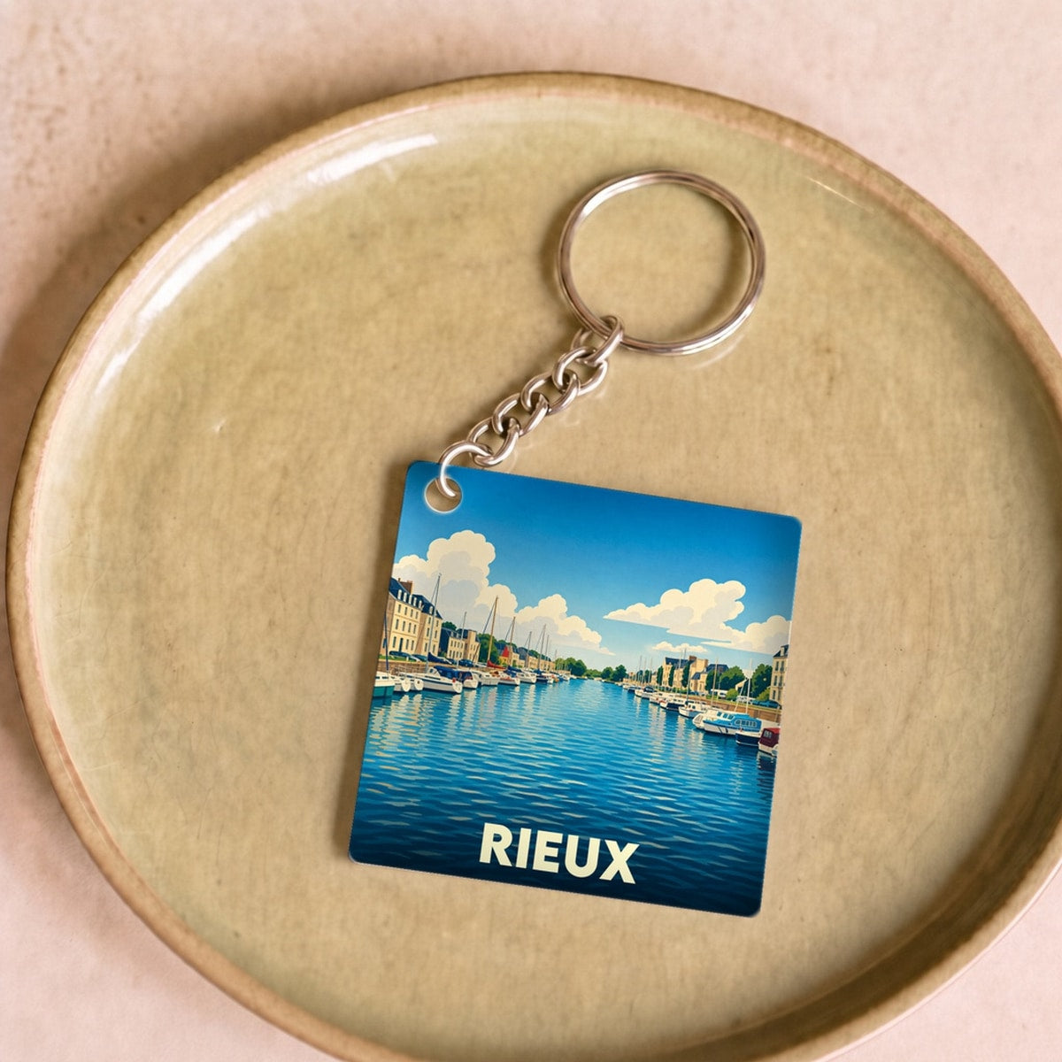 Porte-clés souvenir de la ville de Rieux avec une illustration stylisée de son port.